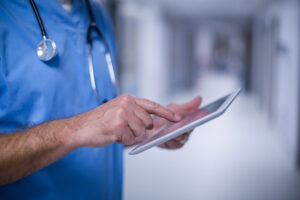 Mid section of male surgeon using digital tablet in operation room at hospital